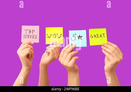 Frauen mit Bewertungen auf lila Hintergrund. Customer Experience-Konzept Stockfoto