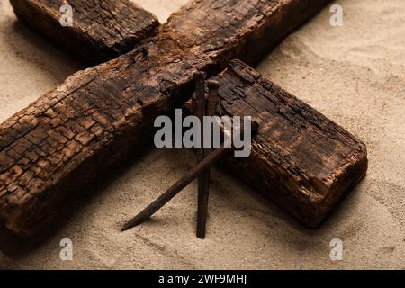 Holzkreuz mit Nägeln auf Sand. Karfreitagskonzept Stockfoto