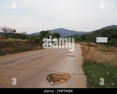 Viele große Schlaglöcher und sehr schlechte Straßenoberfläche der Maguga-Damm-Straße in Piggs Peak, Eswatini. Stockfoto