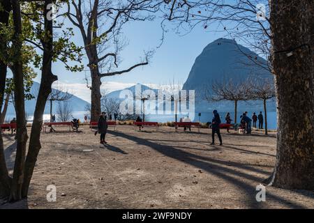 Die Menschen saßen auf Bänken in einem Park am Luganer See in der Schweiz Stockfoto