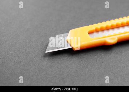 Gelbes Universalmesser auf schwarzer Pappoberfläche. Einzelschneider zum Auspacken von Online-Bestellungen Stockfoto