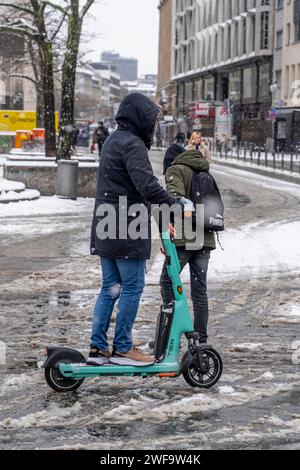 Winter in der Stadt, E-Scooter Fahrer fährt durch verschneite Straßen, Slush, Frankfurt, Hessen, Deutschland Stockfoto