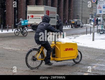 Winter in Frankfurt, DHL Fahrradkurier, Wolt Lieferservice für Lebensmittel, Lebensmittel, im Bankenviertel Hessen, Deutschland Stockfoto