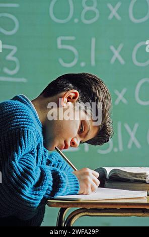 Ein Latino-Schüler, der sich konzentriert und fleißig an seinem Schreibtisch arbeitet und einen mathematischen Auftrag erledigt Stockfoto