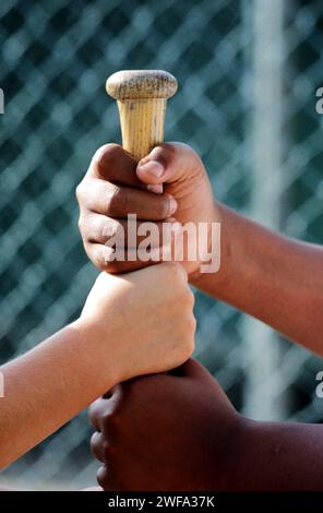 Afroamerikanische und kaukasische Hände greifen einen Baseballschläger in der altehrwürdigen Methode der Wahl Stockfoto