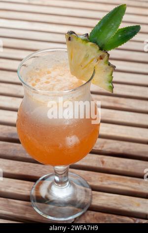 Ein Glas Ananassaft, serviert mit Eis, wird auf den Tisch gestellt. Sieht sehr erfrischend aus Stockfoto