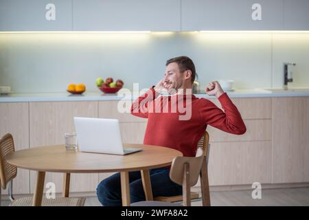Mann freiberuflicher Mitarbeiter, der zu Hause am Laptop arbeitet, glücklich über erfolgreiches Projektende, Pause machen, Ruhe. Stockfoto