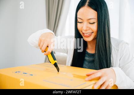 Eine Frau hält einen Universalschneider für präzises Auspacken und enthüllt Online-Shopping-Inhalte Stockfoto