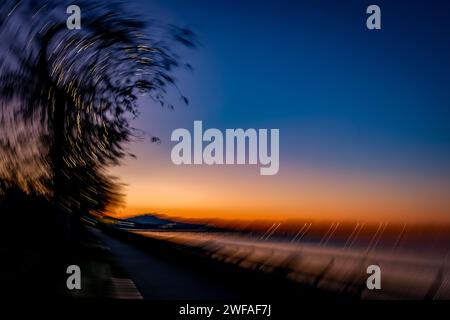Intent Camera Movement (ICM) erzeugt ein einzigartiges Bild des Sonnenaufgangs in White Rock, BC. Kamerabewegungen verschwimmen Ufer, Pier, Berge und Uferpromenade. Stockfoto