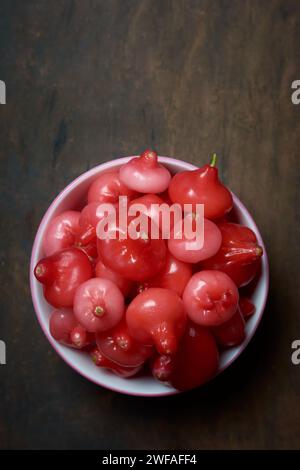 Jambu oder Rosenapfel, alias Glockenfrucht oder Wachsapfel, Fleisch ist knusprig und wässrig, glockenförmig oder birnenförmig saftige Früchte auf rustikalen Holztisch Stockfoto