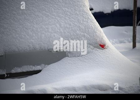 Das Auto ist nach Wintersturm oder Schneesturm von einer dicken Schneedecke umgeben und liegt inmitten einer rauen und eisigen Winterlandschaft. Das Auto verschmilzt fast in den surr Stockfoto