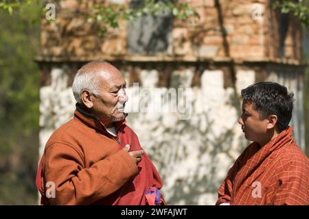 Lama spricht mit einem bhutanischen Mann draußen im Dorf Ugyen Choling, Bhutan, Asien Stockfoto