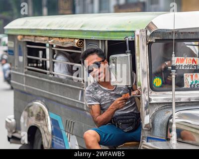 Ein Fahrer eines der beliebten Jeepneys in Manila. Obwohl es Flugzeuge gibt, die sie auslaufen lassen, sind Jeepneys bei weitem das beliebteste Mittel der öffentlichen Hand Stockfoto
