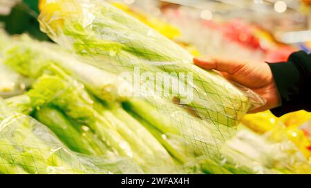 Junger Mann, der Gemüse im Supermarkt kauft. Kaufen Sie einen Haufen Sellerie im Supermarkt. Stockfoto