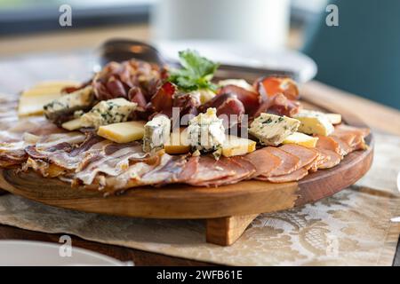Ein hölzernes Schneidebrett mit einer köstlichen Anordnung von verschiedenen Aufschnitt- und Käsesorten. Stockfoto