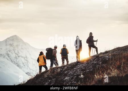 Eine Gruppe von Wanderern aus gemischtem Alter steht am Berghang und sieht den Sonnenuntergang Stockfoto