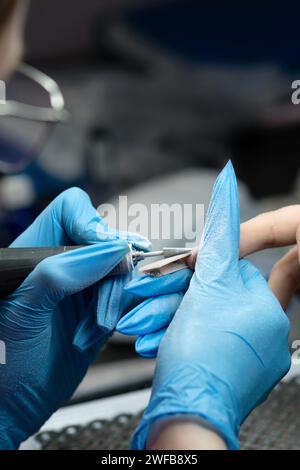 Maniküre verwendet eine elektrische Feile zur präzisen Formung von Kantennägeln. Stockfoto