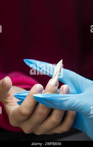 Nahaufnahme der Kantennagelfeile und -Formung während einer Maniküre. Stockfoto