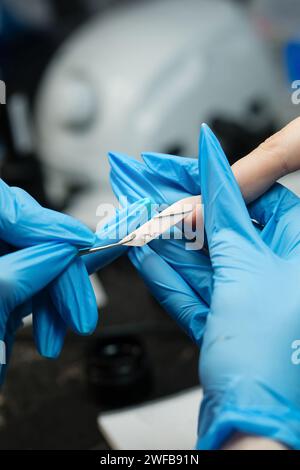 Eine Nahaufnahme eines professionellen Nageltechnikers, der Acrylnägel mit einer elektrischen Handfeile formt und die Präzisionsarbeit in einem Schönheitssalon detailliert beschreibt. Stockfoto