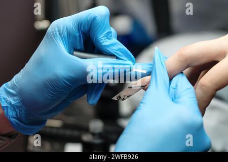 Nahaufnahme der professionellen Nagelmodellierung, die die Präzision eines Nageltechnikers bei der Erstellung einer schlanken Stiletto-Form mit speziellen Werkzeugen in einer Be unterstreicht Stockfoto