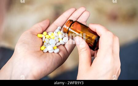 Nahaufnahme einer Frauenhand, die Pillen aus der Pillenflasche auf ihre Hand gießt. Stockfoto