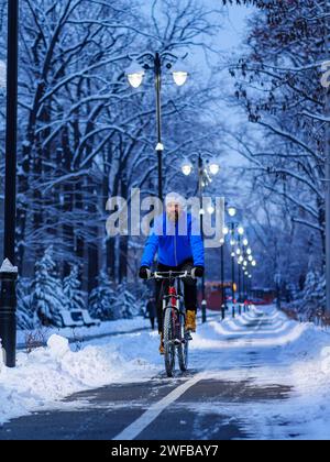 Ein Typ fährt in der Stadt an einem Winterabend auf einem Radweg. Aktiver Lebensstil in der Stadt im Winter Stockfoto