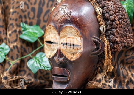 Afrikanische Holzmaske aus Uganda, zum Familien- oder Personenschutz, aus heimischem Holz, Seilen und Muscheln als Haarschmuck Stockfoto