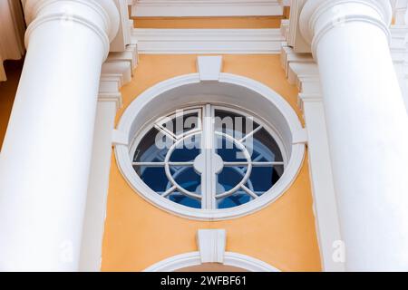 Klassische Architekturdetails, rundes Fenster mit weißem Rahmen in gelber Steinmauer Stockfoto