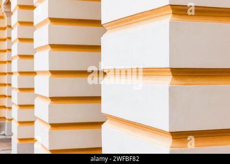 Abstrakte klassische Architekturdetails, weiße Säulen mit gelben Streifen, perspektivische Sicht Stockfoto
