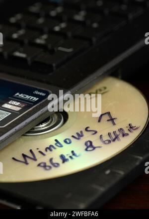 Illegales Installationskonzept für Windows-Software mit Windows 7 86-Bit- und 64-Bit-Riss auf CD, die zur Installation in ein Notebook-Brennerlaufwerk eingelegt werden kann Stockfoto