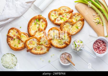 Hausgemachte köstliche traditionelle bayerische Brezeln oder Brezeln gebacken mit Frischkäse, Speck und Zwiebeln Stockfoto