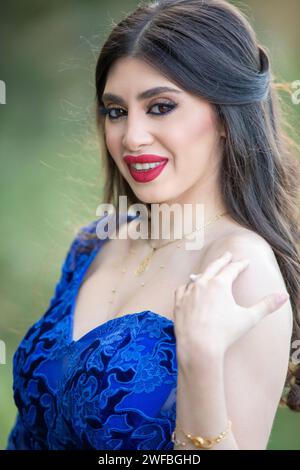 Glückliche, schöne Frau, die Make-up trägt und draußen lächelnd in die Kamera schaut Stockfoto
