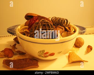 Ein Pot-pourri-Arrangement, dessen Inhalt aus getrockneten, natürlich duftenden Pflanzenmaterialien wie Samenkapseln und Blütenblättern in einer Faience de Quimper-Schüssel gewonnen wird. Stockfoto