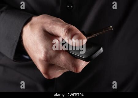 Drücken Sie bei Dunkelheit mit der Hand auf die Fernsteuerung der Alarmanlage. Stockfoto