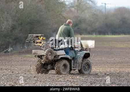 Farmer und schwarz-weiß-Border Collie Hund auf Quad-Bike, der über Land zu einem anderen Feld reist, um zu arbeiten, hat Maschinen in der Quad-Bike-Wintersaison UK Stockfoto