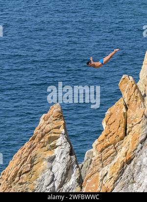 Acapulco, Mexiko - 17. Januar 2024: Einer der berühmten Klippentaucher in La Quebrada taucht von einer hohen Tauchplattform ins Meer Stockfoto