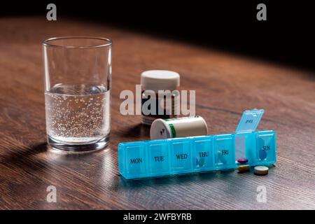 Pillen-Organisator mit verschiedenen Pillen und Ergänzungsmitteln. Wöchentlicher Pillen-Organizer auf dem Tisch. Tägliche Pillenbox mit Medikamenten und Nahrungsergänzungsmitteln. Stockfoto