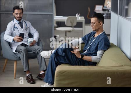 Männliche Ärzte, die digitale Geräte in der Pause verwenden Stockfoto