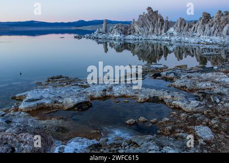 Tuffstein-Formationen spiegeln sich im Mono Lake in Kalifornien in der Abenddämmerung wider. Stockfoto