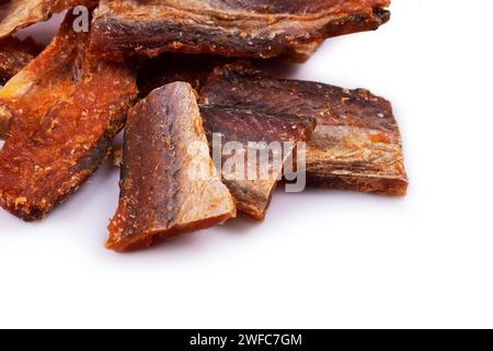 Stücke von gereinigtem, getrocknetem Fisch, isoliert auf weiß. Trocken Gewürzter Pollack. Bernstein mit Pfeffer. Stockfoto