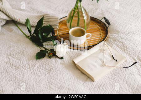 Offenes Buch mit Gläsern, Tasse Kaffee und Blumenstrauß mit weißen pinkfarbenen Pfingstrosen Stockfoto