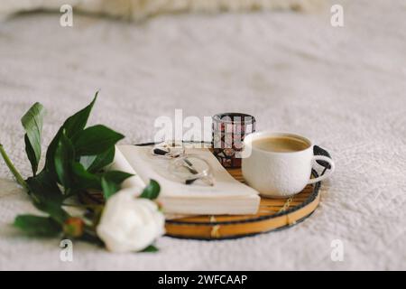 Offenes Buch mit Gläsern, Tasse Kaffee und Blumenstrauß mit weißen pinkfarbenen Pfingstrosen Stockfoto