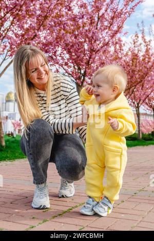 Die ersten Schritte des Babys mit der Hilfe der liebevollen Mutter Stockfoto