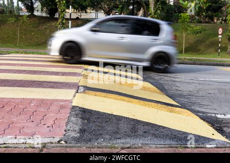 Das Fahrzeug verlangsamt sich bei Geschwindigkeitsschwellen oder Straßenhöhlen, die in gelb-schwarzem Streifen lackiert sind. Beabsichtigte Bewegungsunschärfe. Stockfoto