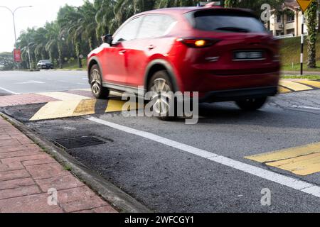 Das Fahrzeug verlangsamt sich bei Geschwindigkeitsschwellen oder Straßenhöhlen, die in gelb-schwarzem Streifen lackiert sind. Beabsichtigte Bewegungsunschärfe. Stockfoto