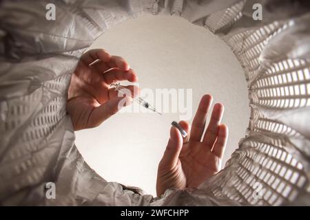 Wirft die Spritze mit der Packung von Hand in den Papierkorb. Innenansicht. Stockfoto