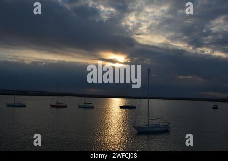 Sonnenuntergang über dem Hafen von Dun Laoghaire mit den vor Anker liegenden Segelbooten und die Sonne reflektiert auf dem Wasser, Dublin, Irland Stockfoto