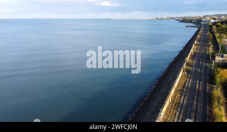 Aus der Vogelperspektive der Bahnlinien in Blackrock, Dublin, Irland an einem sonnigen Tag mit ruhigem Wasser im Meer Stockfoto