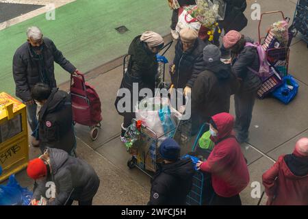 Kunden mit ihren Einkaufswagen und Einkaufstaschen gefüllt mit Großpackungen aus der Essenskammer der Heiligen Apostel in Chelsea in New York am Mittwoch, den 24. Januar 2024. (© Richard B. Levine) Stockfoto