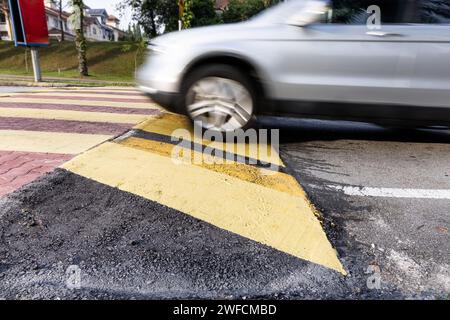 Das Fahrzeug verlangsamt sich bei Geschwindigkeitsschwellen oder Straßenhöhlen, die in gelb-schwarzem Streifen lackiert sind. Beabsichtigte Bewegungsunschärfe. Stockfoto